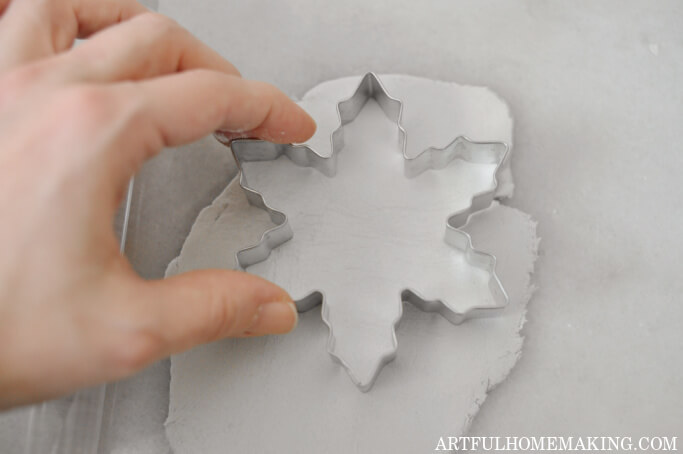 pressing snowflake cookie cutter on clay