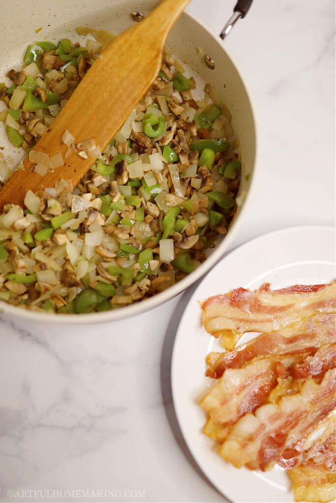 sauteed onions, mushrooms, and green bell peppers in a skillet, and cooked bacon on a plate