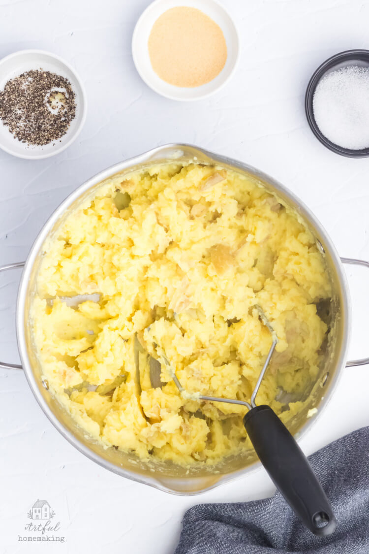 adding seasonings into cooked potatoes and mashing