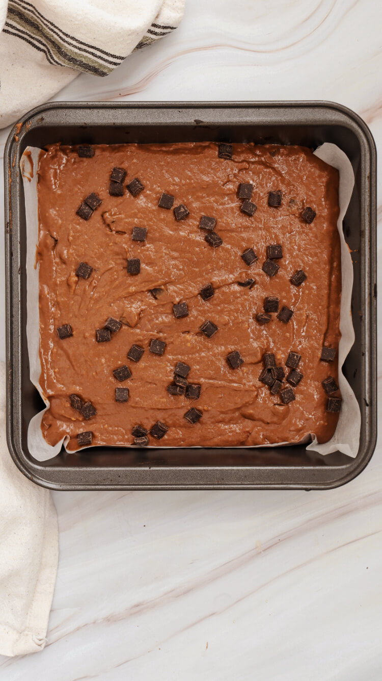 metal pan of brownies with chocolate chunks on top of batter