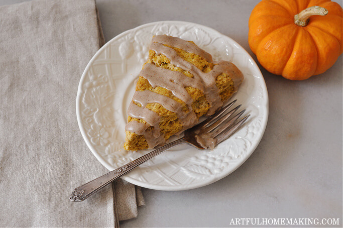 sourdough pumpkin scone with maple glaze on a white plate with a fork