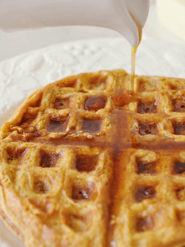 Maple syrup being poured on healthy pumpkin waffles.