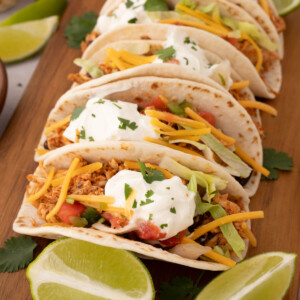 Rotisserie chicken tacos on a wooden cutting board.