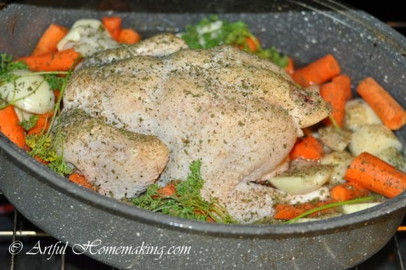 a whole chicken with vegetables in a roasting pan