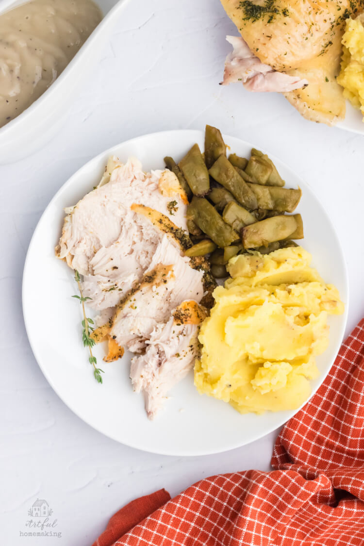 roasted chicken on a white plate with mashed potatoes and green beans