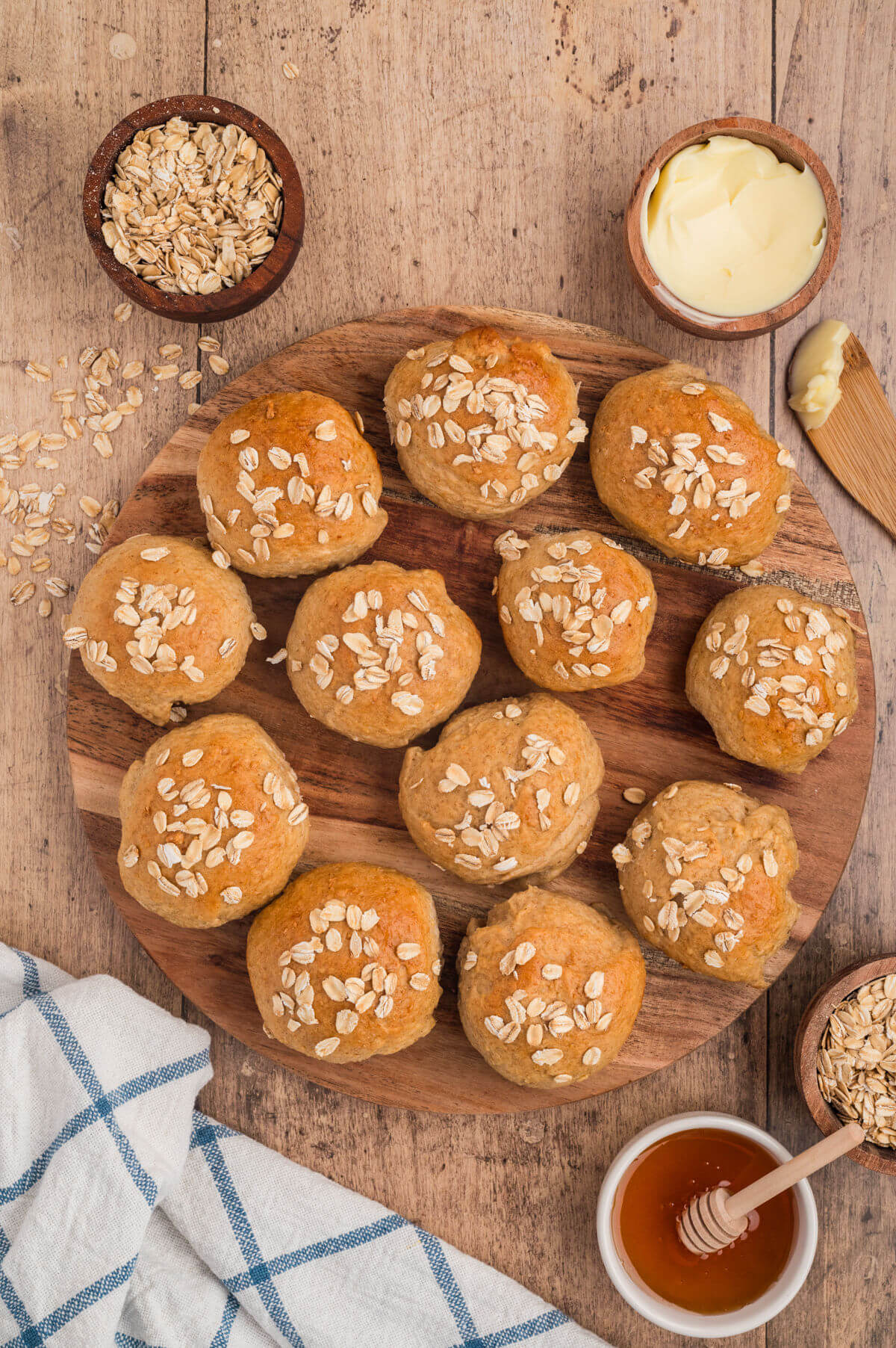 Baked oatmeal dinner rolls on a wooden platter.