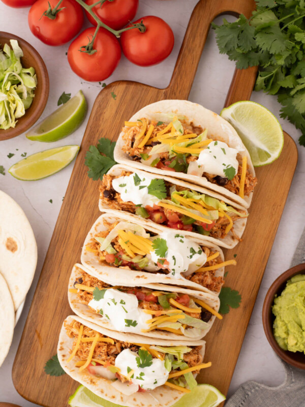 Rotisserie chicken tacos on a wooden cutting board.