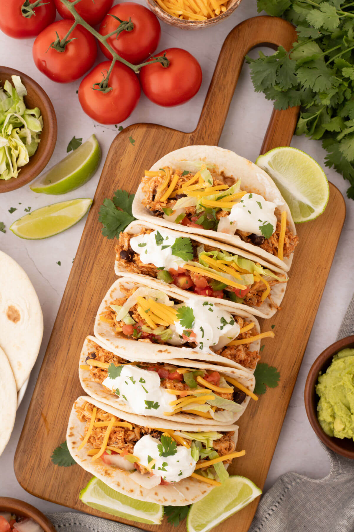 Rotisserie chicken tacos on a wooden cutting board.