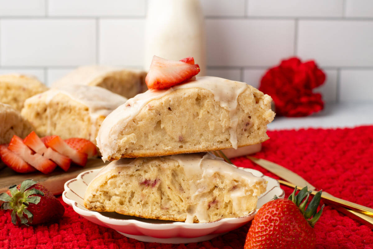 2 freshly made scones piled on a plate with fresh strawberries.