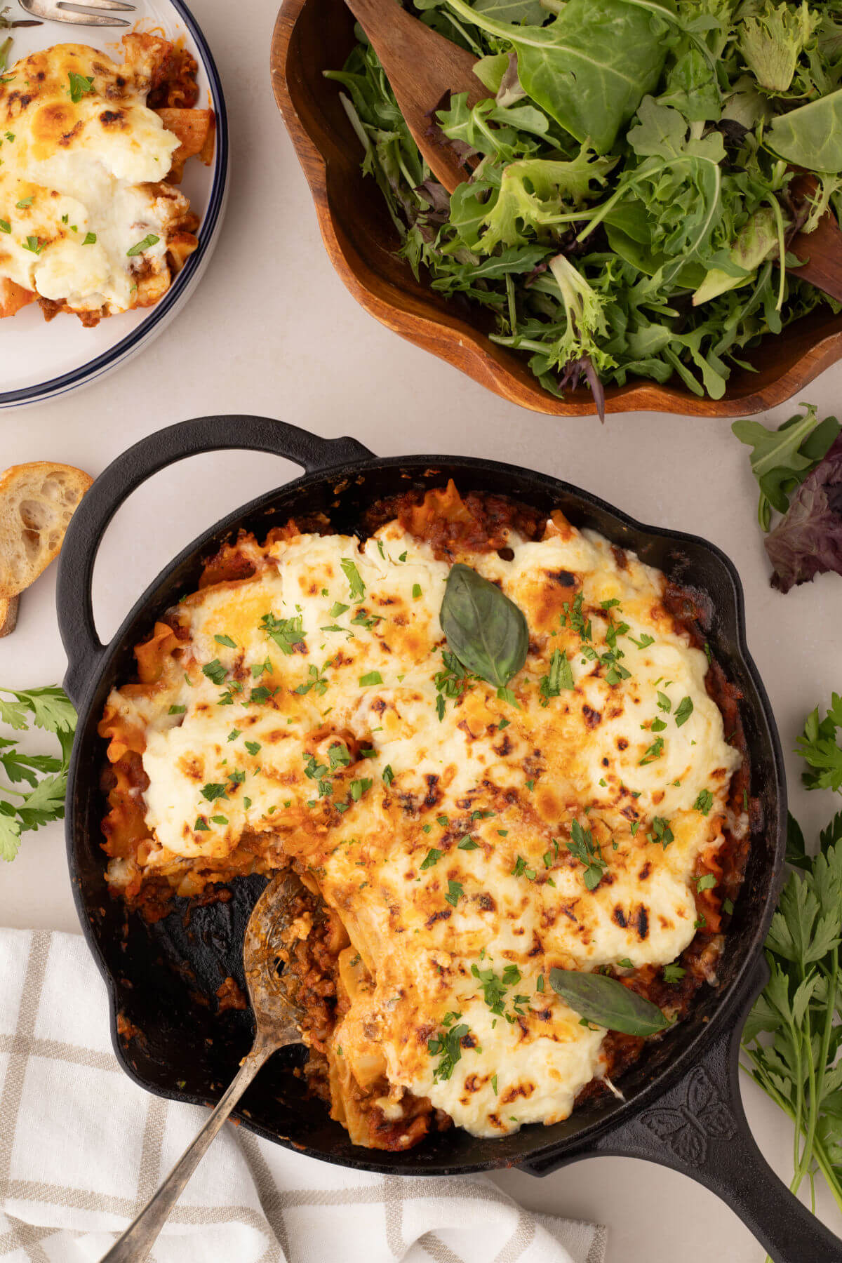 Skillet lasagna in a cast iron skillet with a salad next to it.