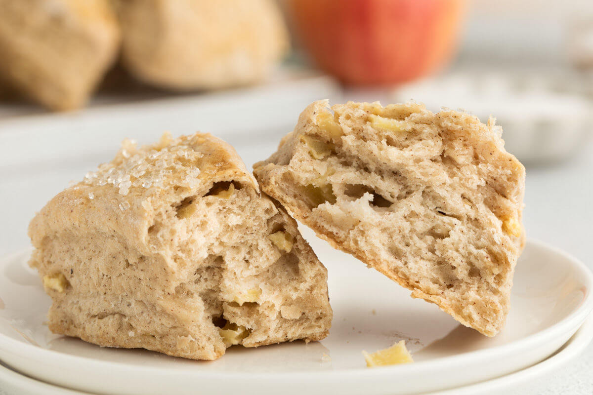 a sourdough apple cinnamon scone broken in two, allowing the flaky inside of the scone to be seen.