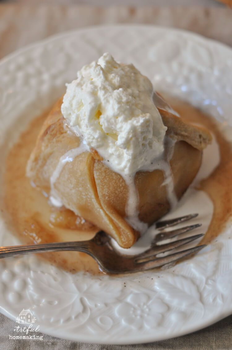 sourdough apple dumpling on a white plate with whipped cream on top