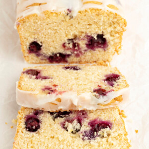Sourdough blueberry bread with icing and 2 slices cut from the loaf.
