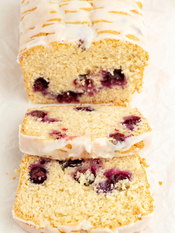 Sourdough blueberry bread with icing and 2 slices cut from the loaf.