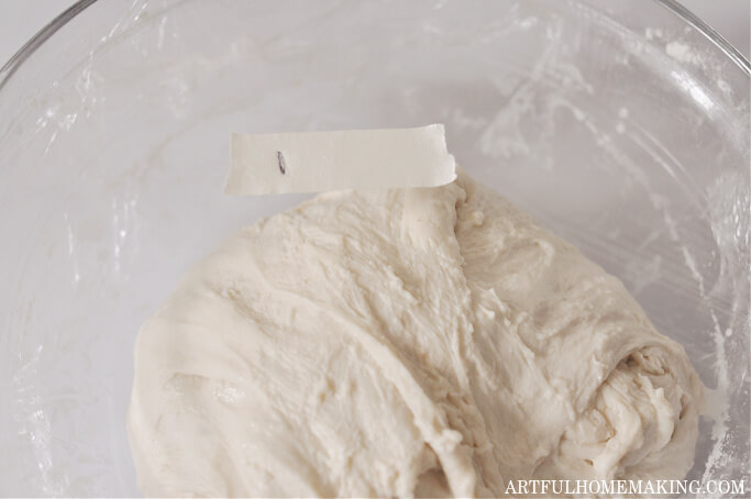 dough in glass bowl after stretch and fold with plastic wrap covering bowl