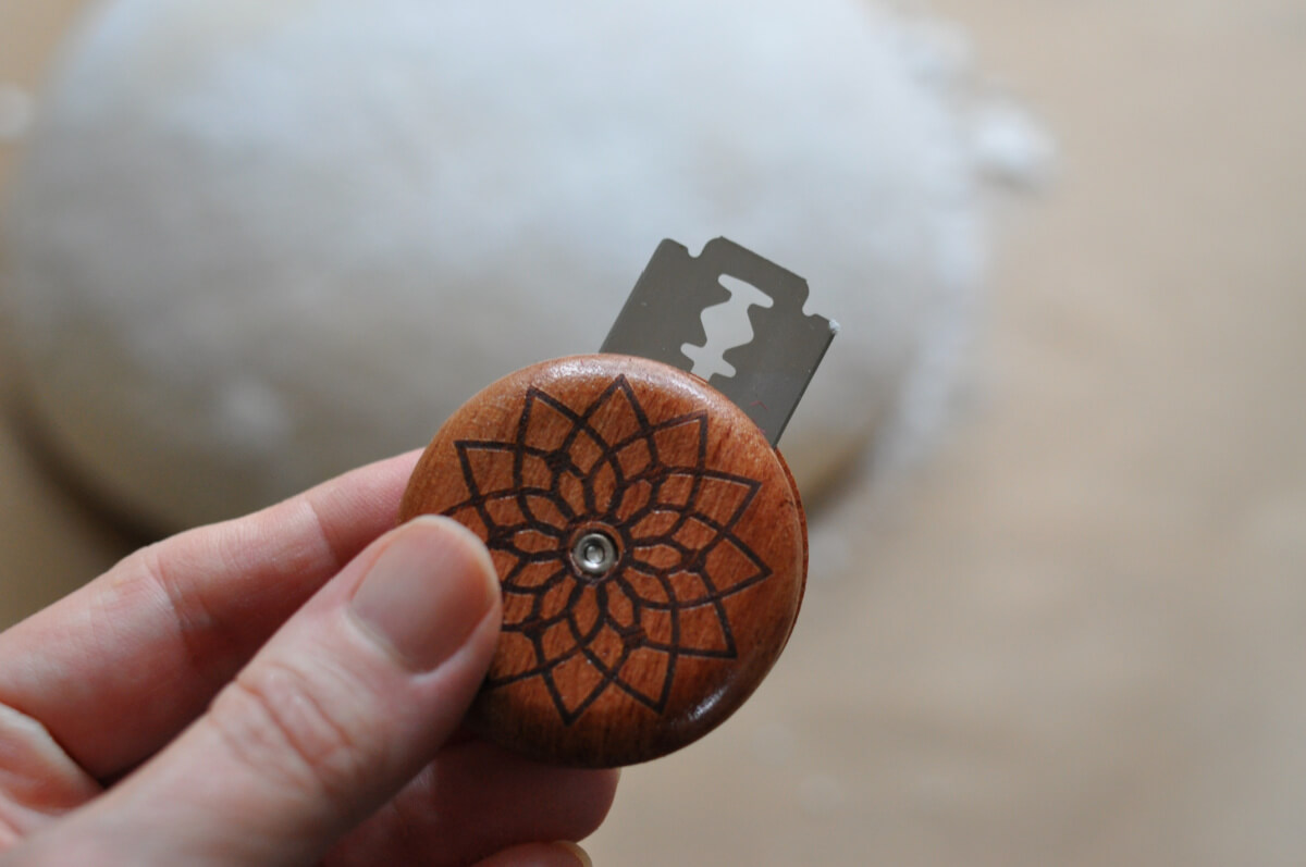 Hand holding up a sourdough bread lame.