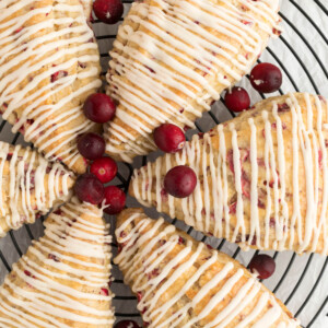 top down view of sourdough cranberry orange scones with fresh cranberries on a wire rack