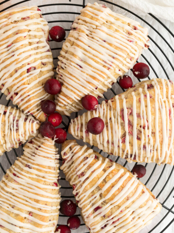 top down view of sourdough cranberry orange scones with fresh cranberries on a wire rack
