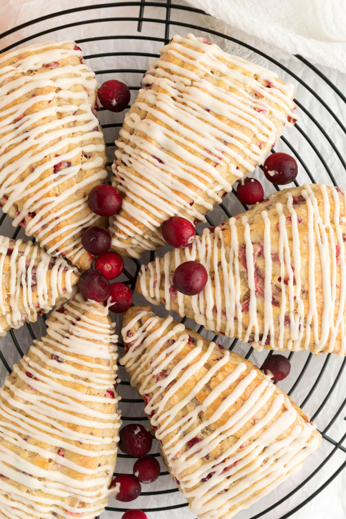 top down view of sourdough cranberry orange scones with fresh cranberries on a wire rack