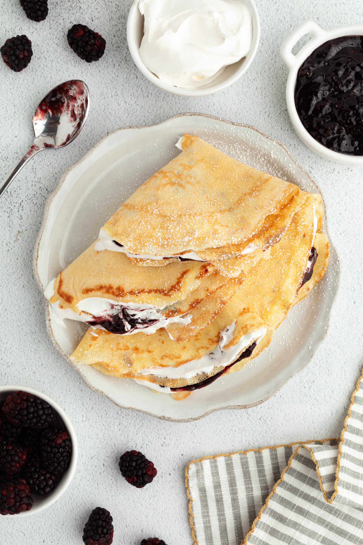 Sourdough crepes on a plate with whipped cream and fruit.