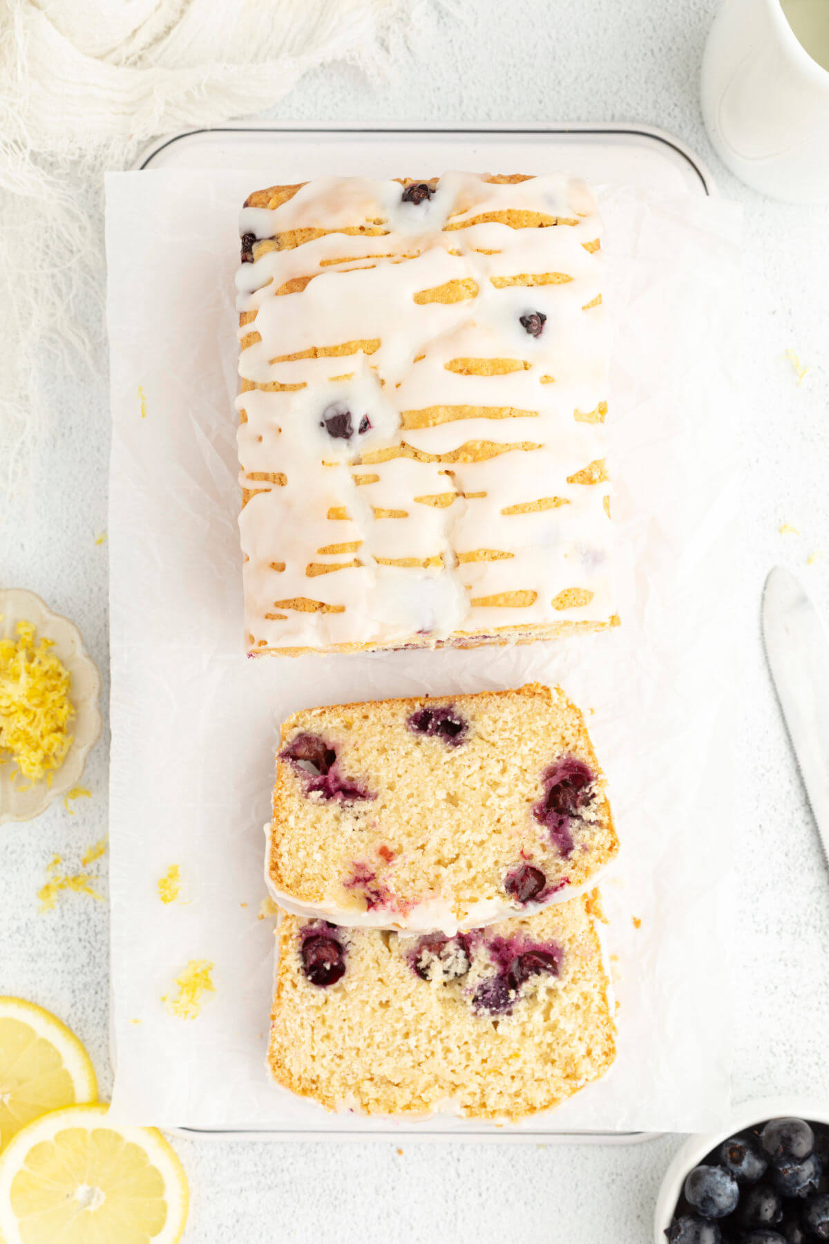 Sourdough lemon blueberry bread with lemon glaze and fresh blueberries and lemons.