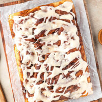 Sourdough discard cinnamon roll focaccia with frosting on a piece of parchment paper.