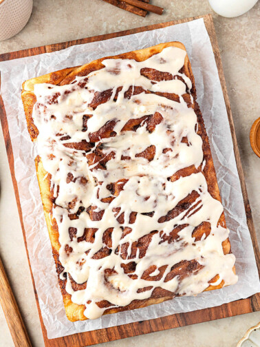 Sourdough discard cinnamon roll focaccia with frosting on a piece of parchment paper.
