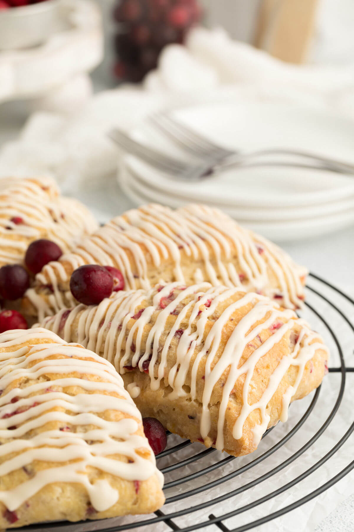 sourdough cranberry orange scones drizzled with glaze on a wire rack