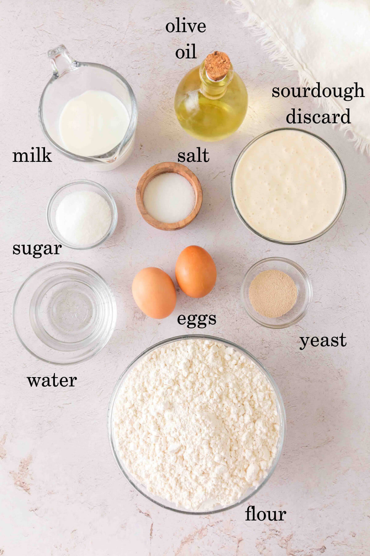 Sourdough discard rolls ingredients in small bowls with text overlay labeling each ingredient.