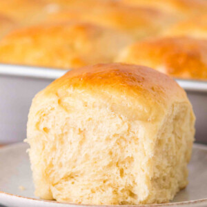 Sourdough discard rolls in a pan with one on a plate.