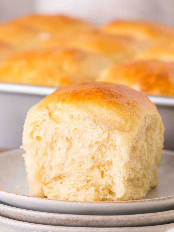 Sourdough discard rolls in a pan with one on a plate.