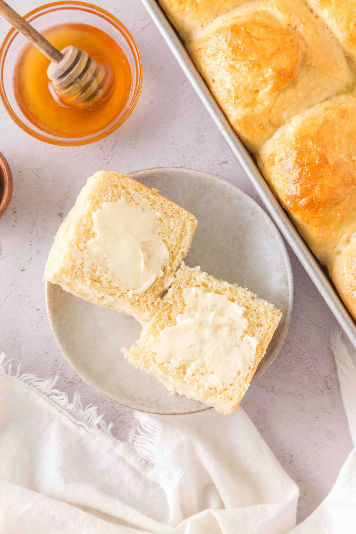 Sourdough discard roll on a plate with butter on both halves.