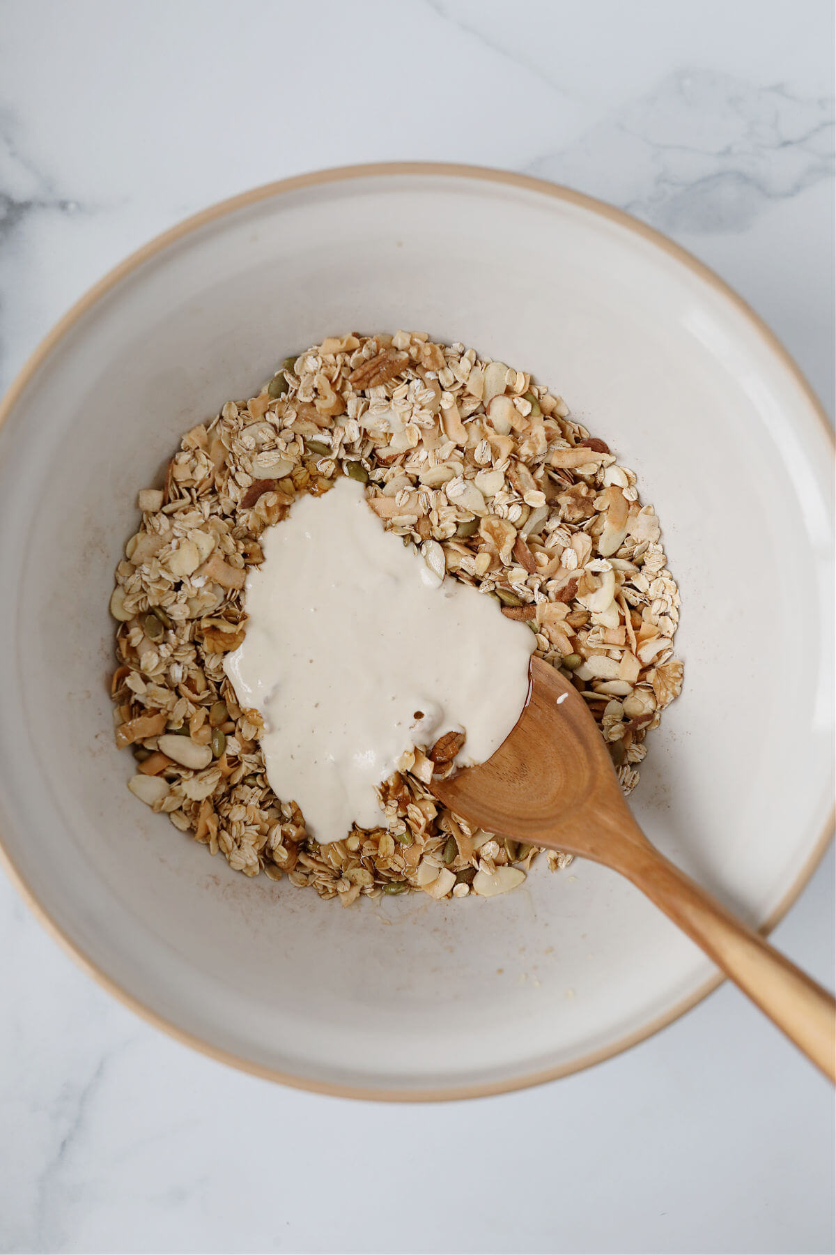 Adding sourdough starter to the bowl of granola.