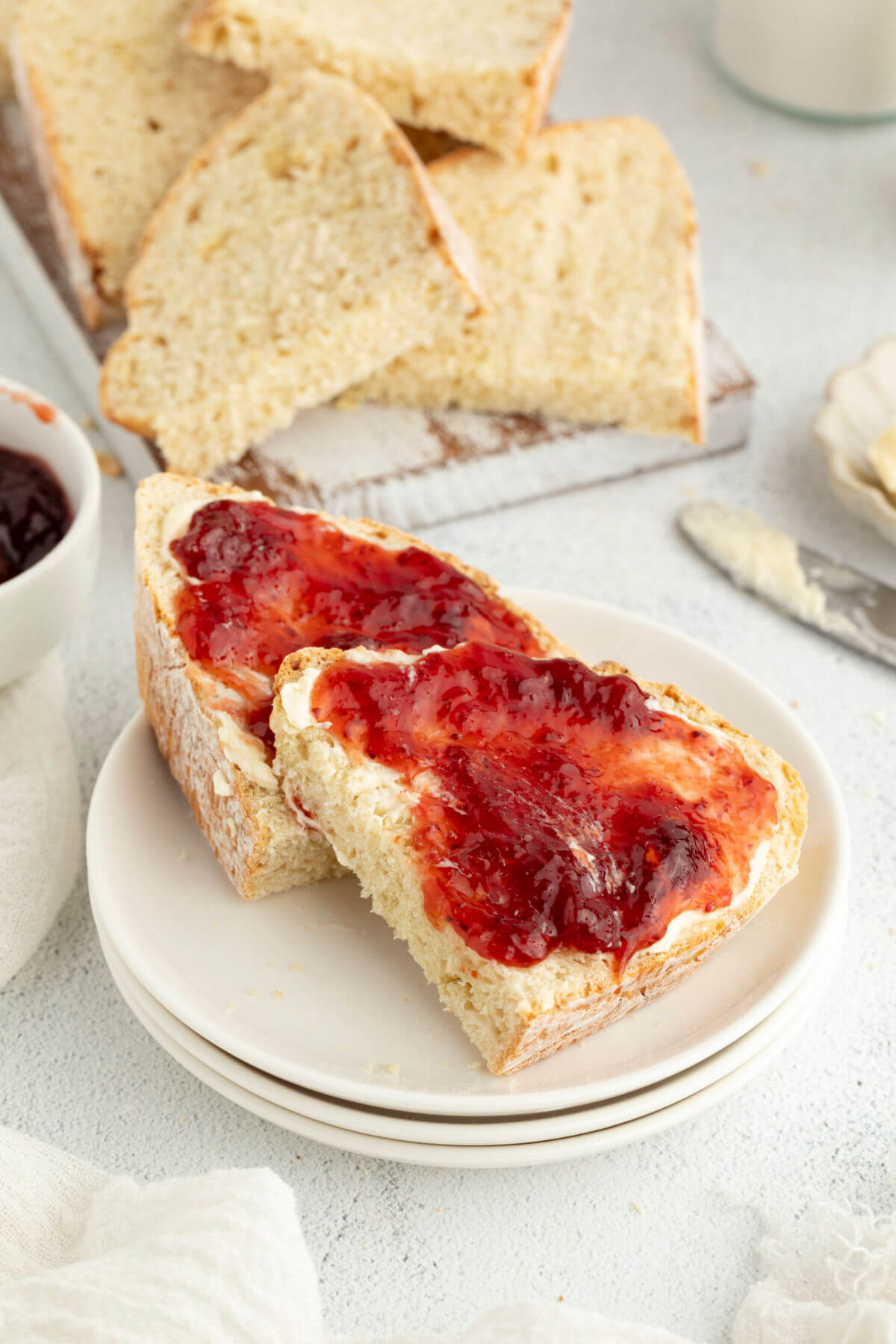 Sliced sourdough Irish soda bread with butter and strawberry jam.