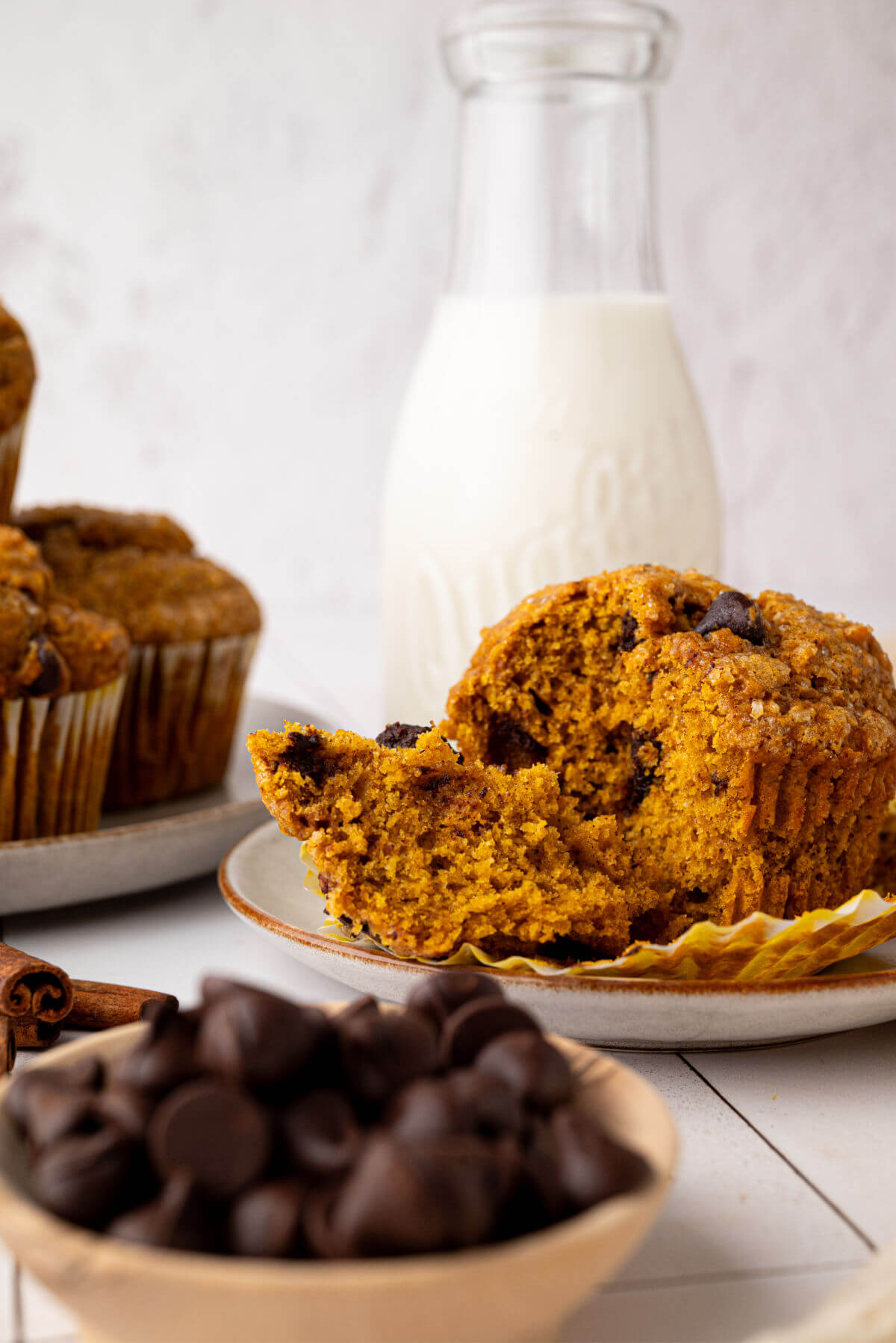 Sourdough pumpkin chocolate chip muffins on a plate next to a bottle of milk.