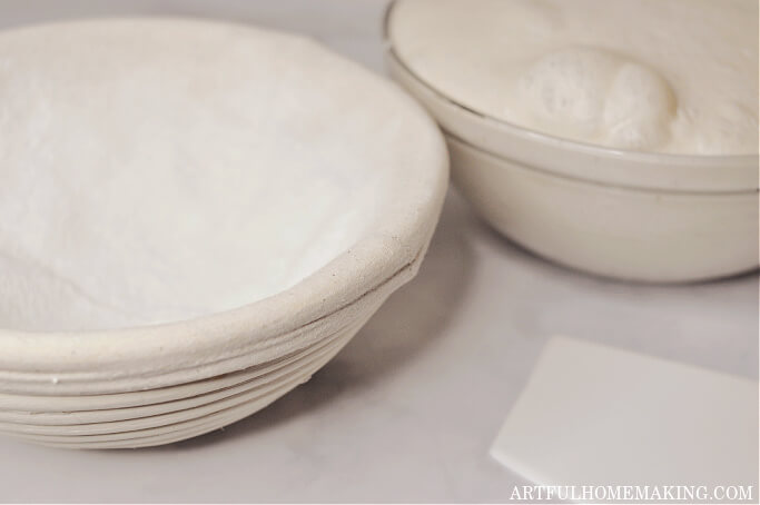 sourdough in glass bowl next to a banneton dusted with rice flour