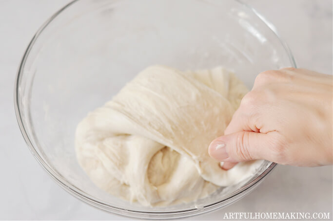 hand pressing dough down into a ball after stretching