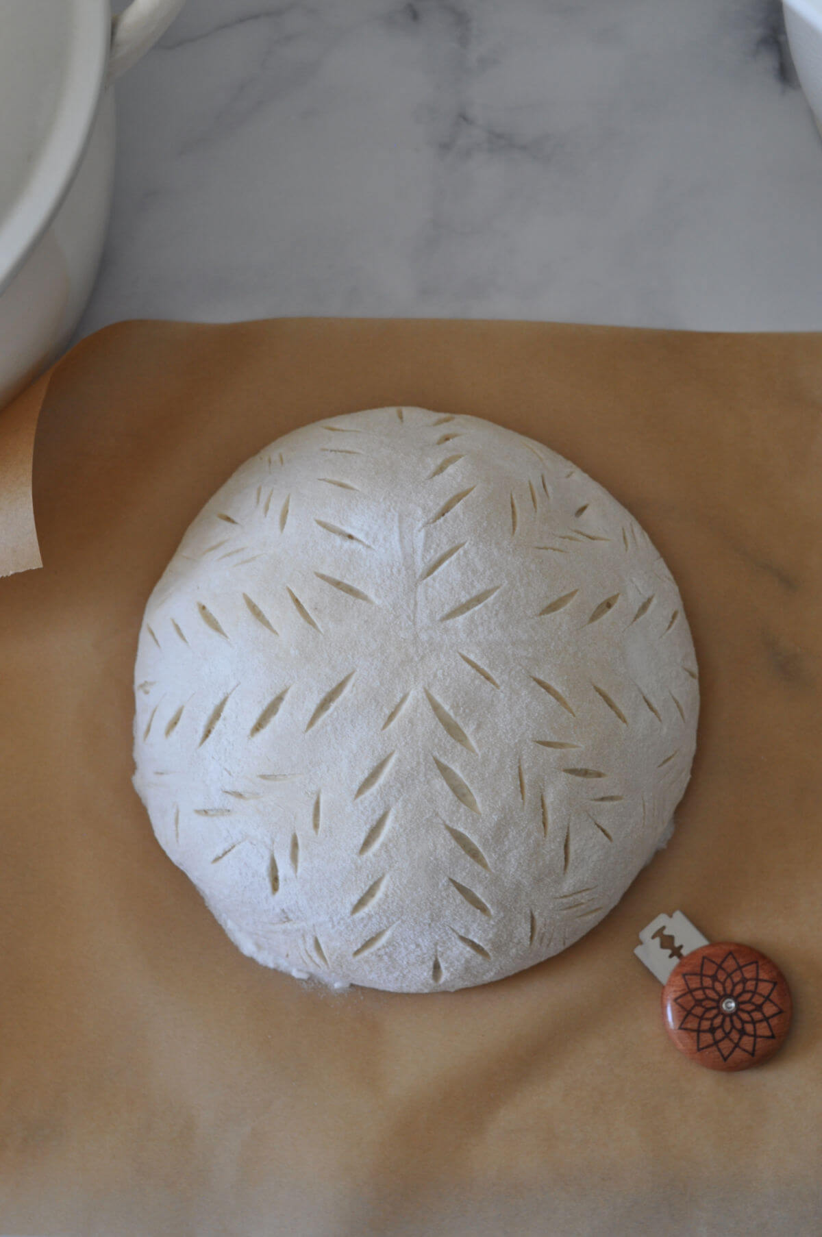 Sourdough artisan loaf after being scored to show what scoring looks like in sourdough glossary.