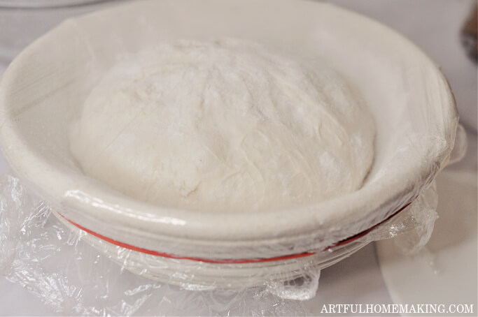 sourdough in banneton with plastic wrap on top ready for cold proofing in refrigerator