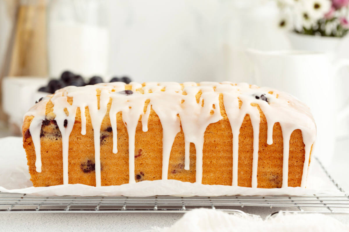 Sourdough blueberry bread with icing dripping down the sides of the loaf.