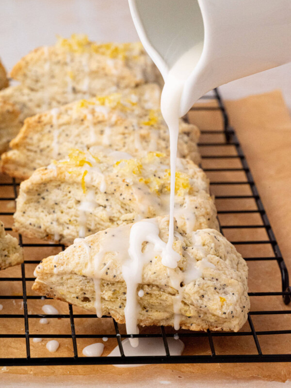 Drizzling lemon glaze on top of sourdough lemon poppy seed scones.