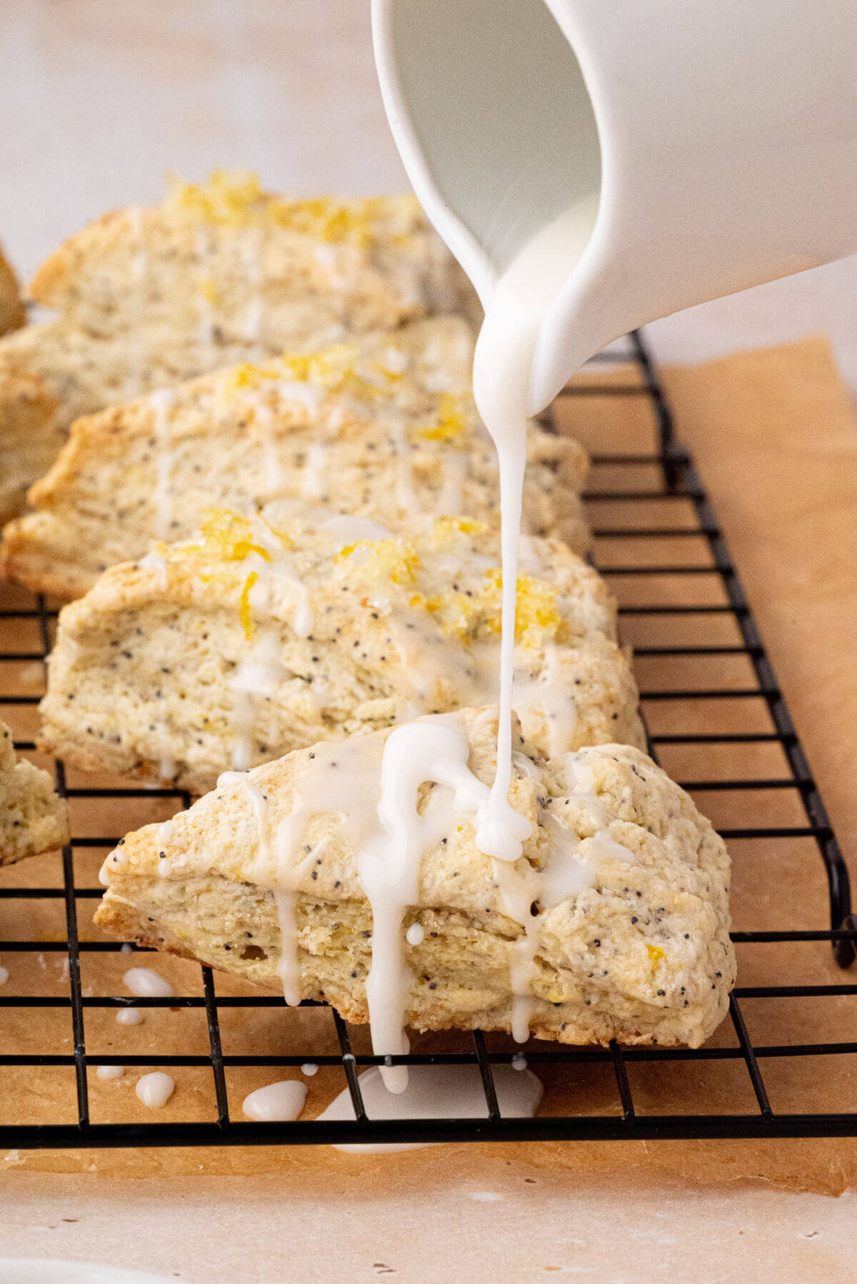 Drizzling lemon glaze on top of sourdough lemon poppy seed scones.