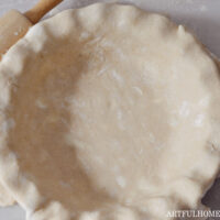 sourdough pie crust in a pie dish with a rolling pin next to it