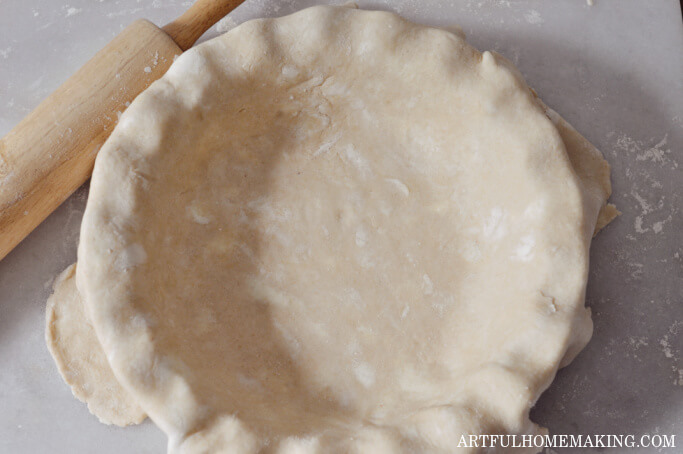 sourdough pie crust in a pie dish with a rolling pin next to it