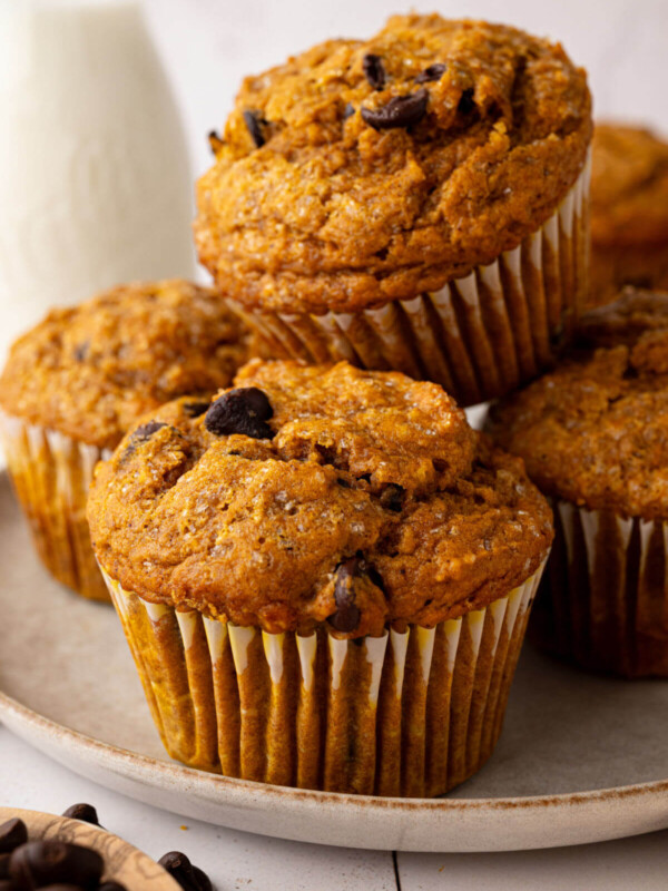 Pile of sourdough pumpkin chocolate chip muffins on a plate.