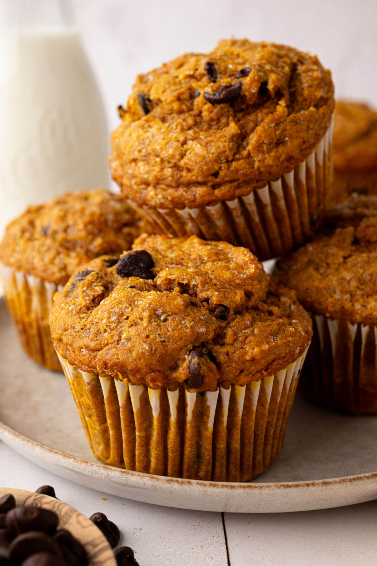 Pile of sourdough pumpkin chocolate chip muffins on a plate.