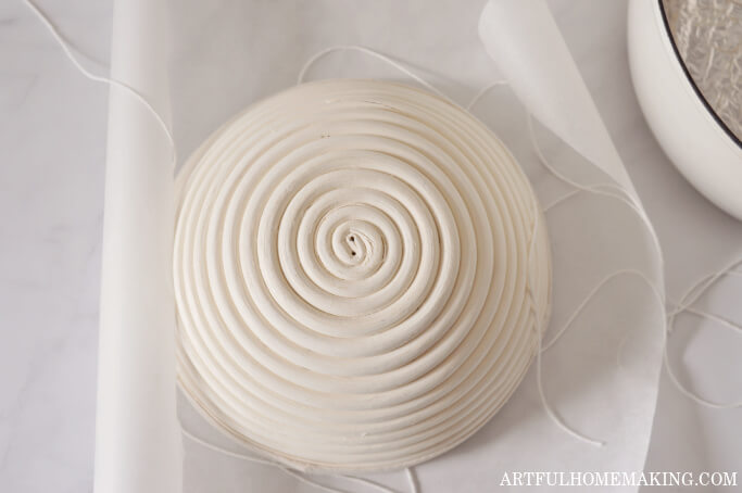 upside down banneton basket on parchment paper with dough underneath