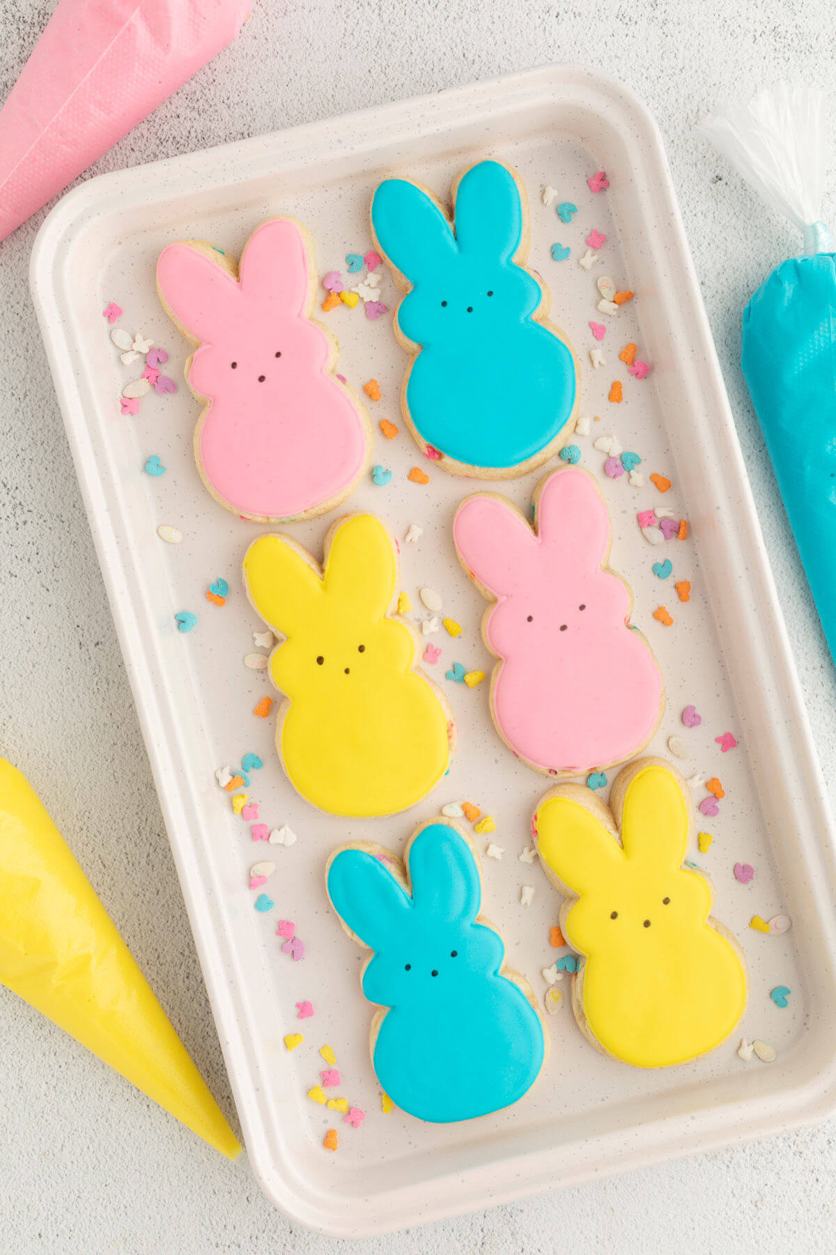 Easter sugar cookies in pink, blue, and yellow on a white tray