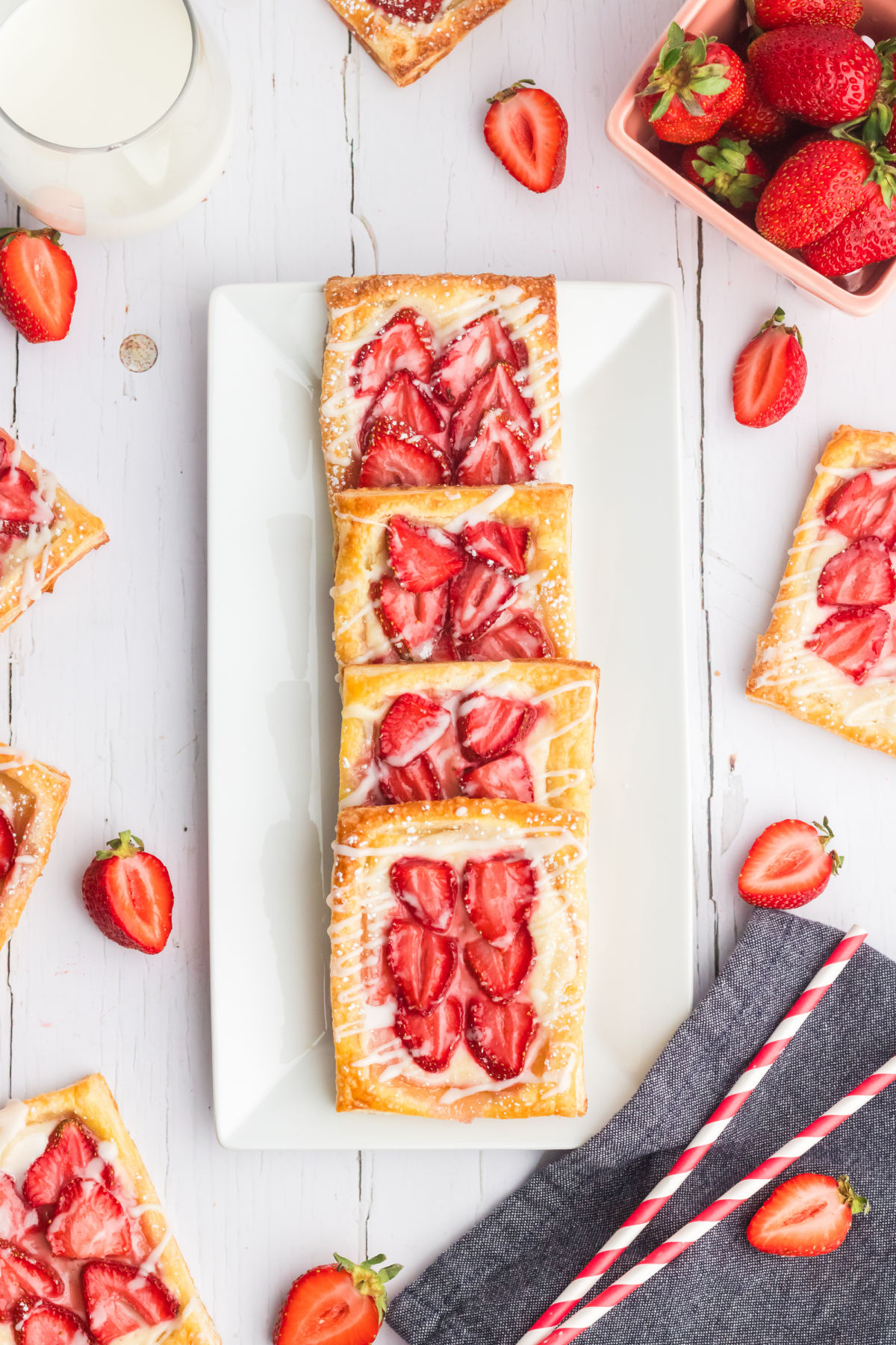 top down view of four strawberry cream cheese danish on a white rectangular serving tray