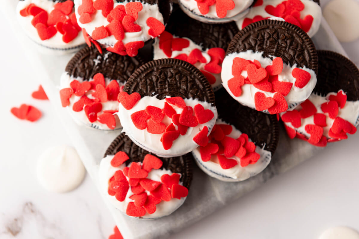 top down view of Oreos dipped in melted white chocolate and covered with heart sprinkles